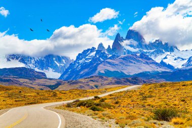 Meşhur Fitzroy Dağı 'na giden yol. Zirvedeki kaya tekelleri güneş tarafından aydınlatılır. Arjantin Patagonya 'sı. Sonsuz düzlükler sarı sonbahar otlarıyla kaplıdır.