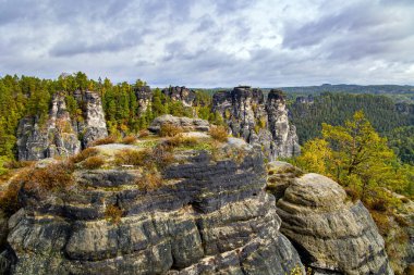 Bastei 'nin resimli kumlu uçurumları. Eski köprü Bastei devlet tarafından korunan mimari bir anıttır. Bulutlu bir sonbahar günü. Almanya. Sakson İsviçre 'ye romantik bir gezi. 