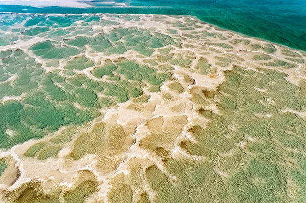Israel. The clear green water of the salty sea. Salt deposits are visible on the seabed. Cold sunny winter day. The photo was taken from a drone. Magic of the Dead Sea.