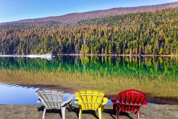 Берегу Озера Стоят Три Разноцветных Пластиковых Стула Гладкая Поверхность Озера — стоковое фото