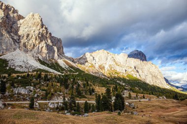 Falzarego geçidi. Doğu Alplerindeki dağ sıraları. Bulutlar gökyüzünde uçuyor. Dolomitlerin renkli kayalarında gün batımı. 