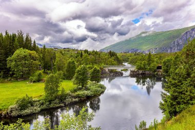 Güçlü bulutlar fiyordun su yüzeyine yansıyor. Su ve yeşillik krallığı. Hardangerfjord 'da. Yaz, Temmuz. Batı Norveç 'in Dağları.