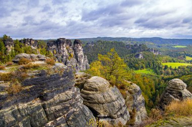 Bastei 'nin resimli kumlu uçurumları. Bulutlu bir sonbahar günü. Almanya. Sakson İsviçre 'ye romantik bir gezi. Eski köprü Bastei devlet tarafından korunan mimari bir anıttır..