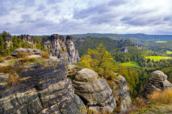 The picturesque sandy cliffs of Bastei. Cloudy autumn day. Germany. Romantic trip to Saxon Switzerland. The old bridge Bastei is architectural monument protected by the state.
