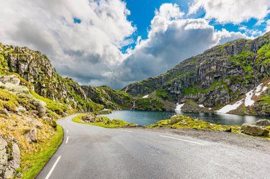 520 nolu yolda karavanla seyahat ediyorum. Dar dağ yolu. Gri kayalar gölün etrafını sarar. Norveç 'te soğuk Temmuz. Dağların yamaçlarında kar tarlaları kaldı.. 
