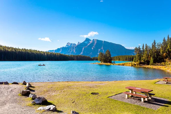 Travel to Canada, the Rocky Mountains. Two Jack Lake. Cozy picnic table and benches. Huge glacial lake reflects the sun. Beautiful autumn day.