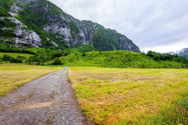 Magnificent Norway. The road to the mountain lake Bondhuswatnet. Journey to the fabulous northern country in the middle of summer. Emerald green of summer grass. 