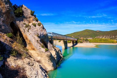  Indian summer in northern Spain. The La Penia Reservoir collects the waters of the Gallego River. La Jolla de Huesca. Picturesque cliffs, bridge and backwater. Wonderful autumn day.