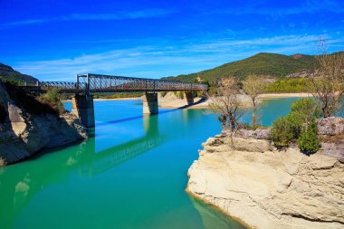 Picturesque cliffs, still water and bridge. Indian summer in northern Spain. The La Penia Reservoir collects the waters of the Gallego River. Wonderful autumn day.