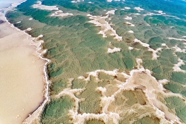 Landscape photographed from a drone. The clear green water of the salty sea. Salt deposits are visible on the seabed. Cold sunny winter day. Israel. Magic of the Dead Sea. 