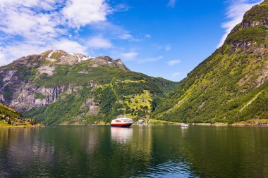 The largest, most beautiful and famous Norwegian fjord Geiranger. Ocean liner is moored at the pier. Warm sunny day in July. Northern Europe. Summer trip to Norway.