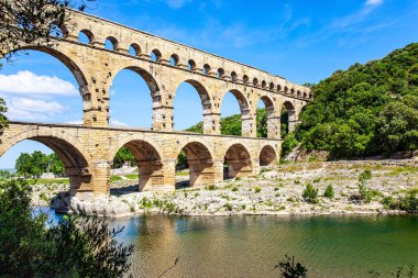 The aqueduct  Pont du Gard is a three-tiered arcade of yellow-pinkish limestone. The shallow Gardon River. The Pont du Gard is the tallest Roman aqueduct. Interesting trip to France 