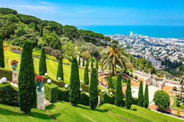 Israel. View from Mount Carmel to the international seaport of Haifa. Clear sunny day by the sea. Gorgeous colorful gardens, flower beds, cypress trees and green lawns attract tourists. 