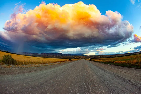 巨大な絵のように美しい雷雲が落雷によって刺し込まれ 日没によって照らされます アルゼンチンのパタゴニアで有名な未舗装道路Ruta 草原はオレンジの草で覆われています — ストック写真