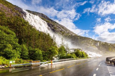 Soğuk yaz günü. Kademeli Langfossen şelalesi otobanla kesişiyor ve Acre Fjord 'a akıyor. Batı Norveç.