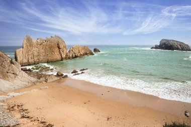 Playa de la Arnia plajı. İnanılmaz jeolojik oluşumlar turistleri şaşırtır. Kıyı kayalarında deniz dalgaları kırılır. Kar beyazı deniz köpüğü donuk sonbahar güneşinde parlar. Cantabria, İspanya.