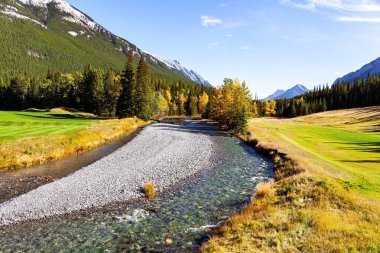 Kıçı çakıllı sığ bir akıntı. Rundle ve Cascade Dağları 'nın eteklerindeki golf sahaları. Kanada 'nın Rocky Dağları' ndaki küçük Banff kasabasının çevresi.