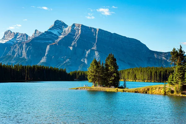 The famous Rocky Mountains, Two Jack Lake. Small picturesque island off the coast is overgrown with pine trees. Huge glacial lake reflects the sun. Travel to Canada.