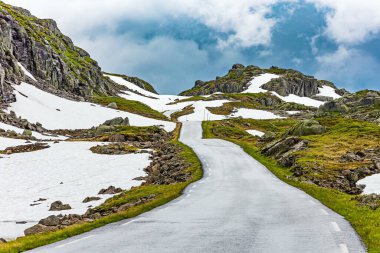 Traveling by camper on road 520. Narrow dangerous mountain road glitters from the rain. cold July in Norway. Large snowfields remained in the slopes of the mountains. clipart
