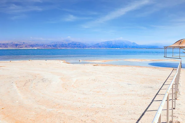 死海可爱的圆形雨伞能遮挡阳光 铁路把通往水的道路圈起来了 中东无水盐湖 以色列海岸 — 图库照片