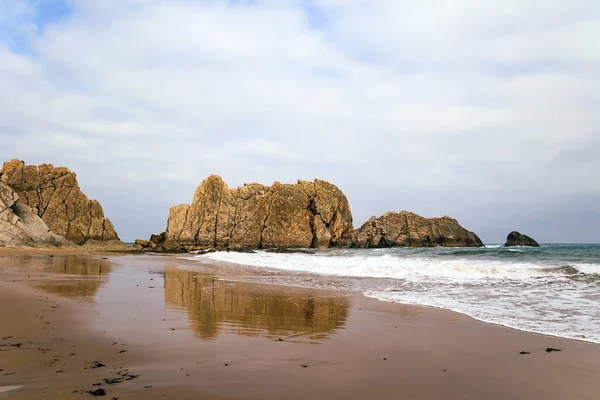 海滩上光滑的湿沙滩反映了岩石的巨石 阿纳尼亚平原海滩 西班牙坎塔布里亚 风景如画的地质构造使游客大吃一惊 白雪公主的泡沫闪闪发光 — 图库照片