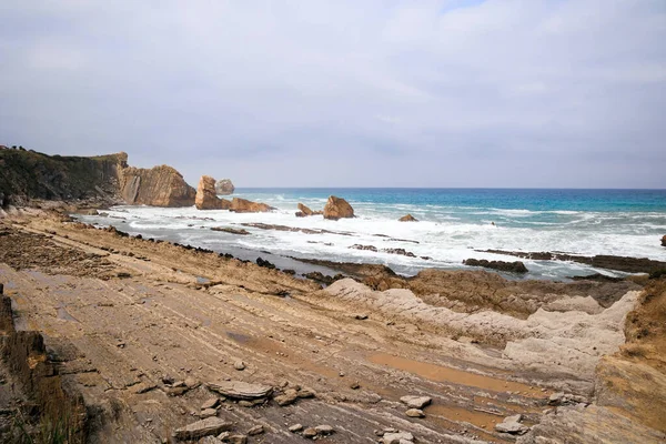 プラヤ アルニアビーチの元の岩棚 スペインのカンタブリア州 絵のように美しい海岸の崖 素晴らしい地質学的形成 素晴らしい観光客 — ストック写真
