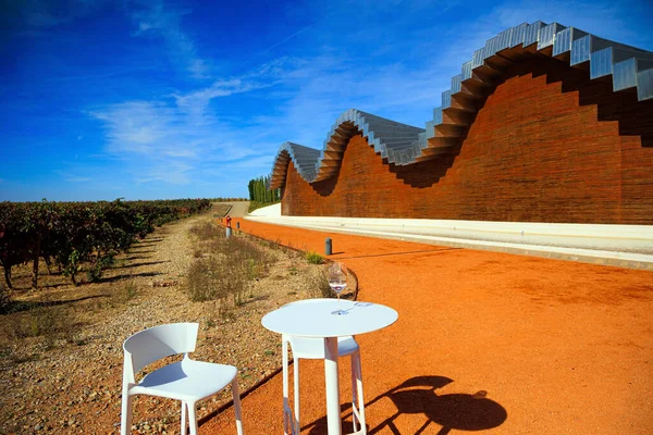 游客的餐桌和椅子 立面的碎片 波浪形酒厂屋顶 Winery Bodega Bodegas Ysios 去温暖的西班牙秋天的旅程 — 图库照片