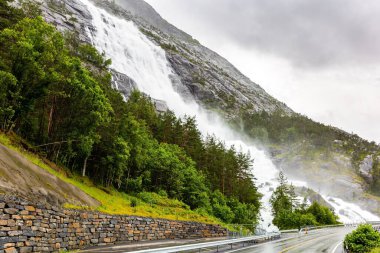 Kademeli Langfossen şelalesi otobanla kesişiyor ve Acre Fjord 'a akıyor. Yaz soğuğu ve yağmurlu bir gün. Batı Norveç. 