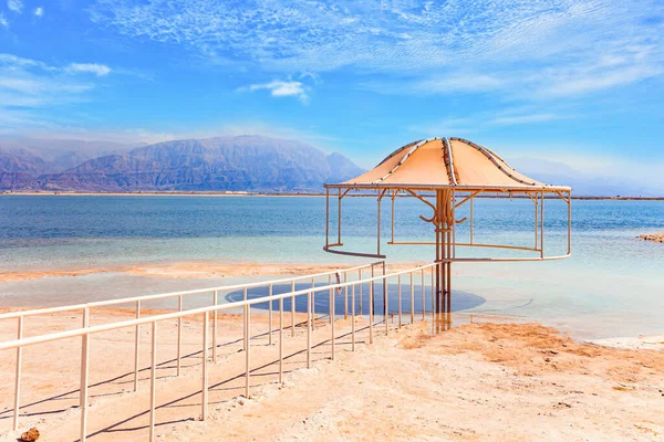 可爱的圆形雨伞能遮挡阳光 铁路把通往水的道路圈起来了 中东无水盐湖 死海以色列海岸 — 图库照片