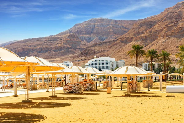 死海以色列海岸 海滩椅子堆放在海滩上 可爱的圆形雨伞能遮挡阳光 中东无水盐湖 — 图库照片