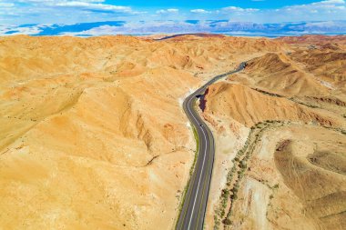 Kuş bakışı, İHA 'dan. Sarımsaklı ve bej kil kaplı kurumuş, susuz tepeler. Ölü Deniz kıyısındaki Yahudi çölü. Tepelerin arasına muhteşem bir yol döşenmiş. İsrail