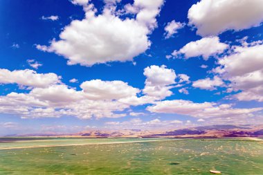 Harika Ölü Deniz. İnsansız hava aracı görüntüleri. Buharlaştırılmış tuz sudan çıkar. Su, gökyüzünün parlak mavisini yansıtır. Bereketli kümülüs bulutları suya yansıyor. İsrail. Parlak Mart günü. 