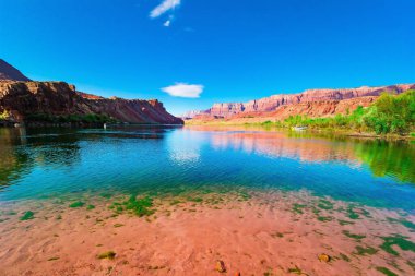 Kırmızı, turuncu ve sarı Navajo kumtaşlarından oluşan çok renkli kanyon. Colorado Nehri 'nin suyu dik kayaları yansıtır. Colorado Nehri 'ndeki tarihi Lees Feribotu.