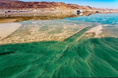 Deniz tabanında tuz birikintileri görülebilir. Ölü Deniz 'in Büyüsü. Tuzlu denizin berrak yeşil suyu. Fotoğraf bir İHA 'dan çekilmiş. Soğuk güneşli bir gün. İsrail
