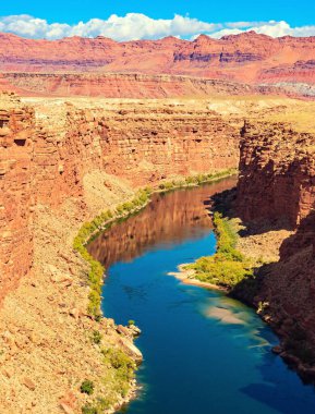 Biziz. Colorado Nehri 'nin derin ve dar kanyonu. Kırmızı Navajo kumtaşlarının çok renkli kanyonu. Colorado Nehri 'nin suyu etrafındaki kayaları yansıtır..
