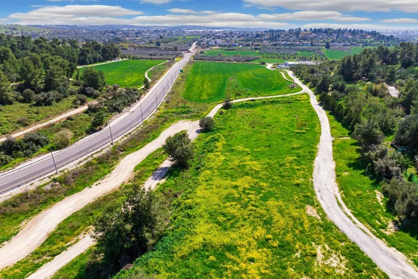 The picture was taken from a bird\'s eye view. The picturesque and green forest in the center of Israel.  Asphalt highway, dirt roads and rural fields. Forest Ben Shemen.