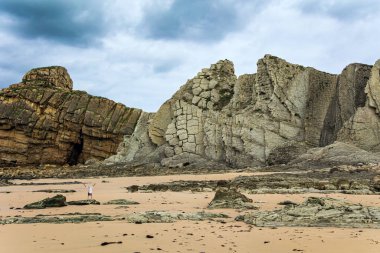 İspanya 'nın Playa di Arnia plajında öğle vakti. Muhteşem manzaraya hayran bir adam. Cantabria 'da. Atlantik kıyısında rüzgarlı bir gün. 