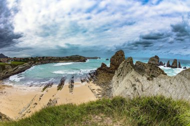 Dev, pürüzsüz gri kayalar ve pürüzsüz kumsal. İspanya 'nın Playa di Arnia plajında öğle vakti. Cantabria 'da. Kayalık okyanus kıyısı. Atlantik kıyısında rüzgarlı bir gün. 