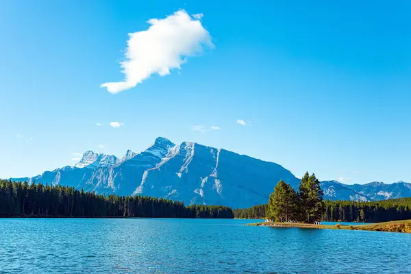 The famous Rocky Mountains, Two Jack Lake. Small picturesque island off the coast is overgrown with pine trees. Huge glacial lake reflects the sun. Autumn Indian Summer in Canada