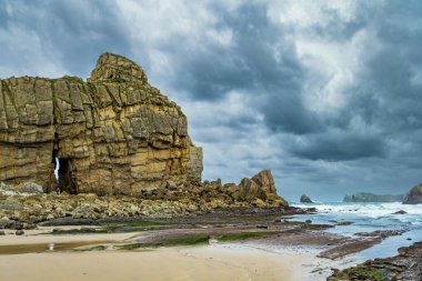 İspanya 'nın Playa di Arnia plajında öğle vakti. Rocky resimli okyanus kıyısı. Cantabria 'da. Atlantik kıyısında rüzgarlı bir gün. 