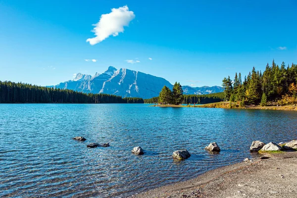 Travel to Canada. Magnificent Banff Park, the Rocky Mountains, Two Jack Lake. Huge glacial lake reflects the sun and cloud. Autumn Indian Summer in Canada