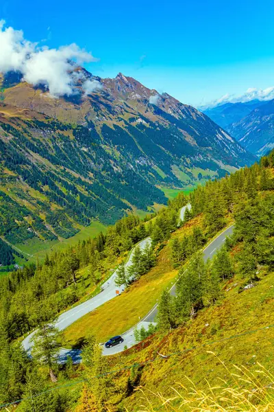 Austria. Snowy mountain peaks covered with clouds. Flowering alpine meadows and mountains of the Hohe Tauern Park. The famous mountain road Grossglognerstrasse.