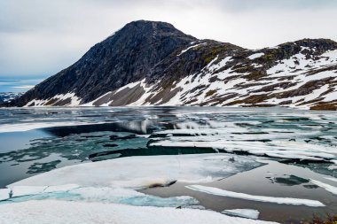 Temmuz ayında Djupvatnet Gölü 'nün çok soğuk ve berrak suyu buzla kaplıdır. Dağlar yeni yağmış karla kaplıdır. Kar Kraliçesi Krallığı. Norveç 'te sihirli yerler. 