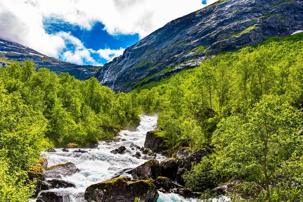 Gorgeous sunny weather in Norway. Travel to fabulous Scandinavia. Stormy rocky mountain stream flows among the majestic mountains
