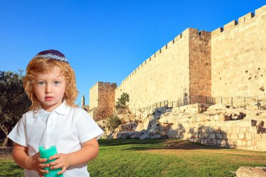 Örgü örmüş, sarışın, küçük bir çocuk. Gün batımında Kudüs 'ün eski ve güçlü duvarları. Kudüs İsrail 'in başkentidir.. 