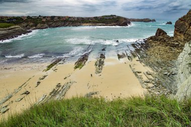 Dev, pürüzsüz gri kayalar ve pürüzsüz kumsal. İspanya 'nın Playa di Arnia plajında öğle vakti. Rocky resimli okyanus kıyısı. Cantabria 'da. Atlantik kıyısında rüzgarlı bir gün. 
