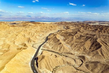 Ölü Deniz 'in kıyılarında çöl. Asfalt karayolu tepeler arasında yol alır. Ölü Deniz çamuru iyileştirici özelliklere sahiptir. Kuş bakışı. İsrail. 