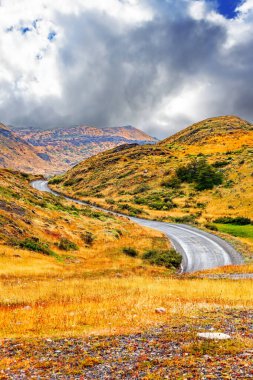 Torres del Paine Ulusal Parkı. Yol tepelerin arasından esiyor. Şili Patagonya 'ya egzotik yolculuk.