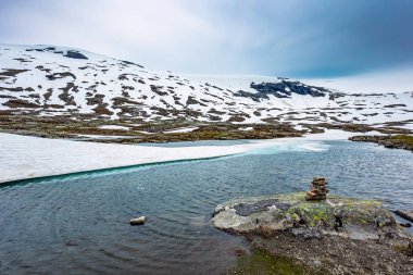 Norveç 'te büyülü yerler. Dağlar yeni yağmış karla kaplıdır. Kar Kraliçesi 'ne yaz gezisi. Temmuz ayında Djupvatnet Gölü buzla kaplıdır.. 