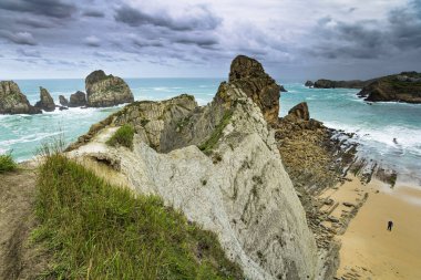 Dev, pürüzsüz gri kayalar ve pürüzsüz kumsal. İspanya 'nın Playa di Arnia plajında öğle vakti. Cantabria 'da. Kayalık okyanus kıyısı. Atlantik kıyısında rüzgarlı bir gün. 